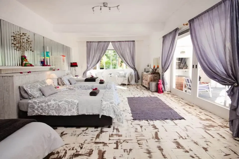 Bright bedroom with three beds large windows and patterned wooden floor
