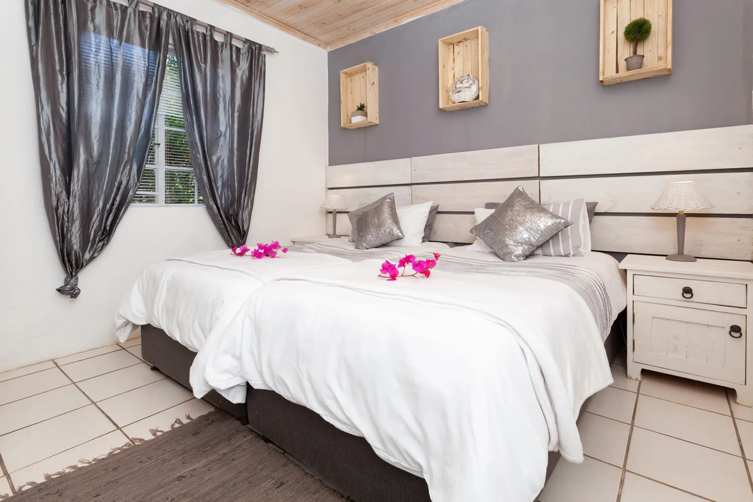 Two neatly made beds with pink flowers in a modern lightfilled bedroom