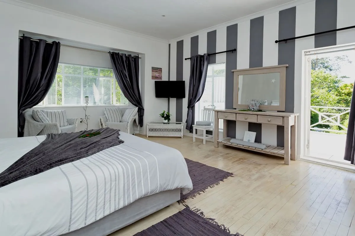 Bright bedroom with large windows striped walls and wooden floor