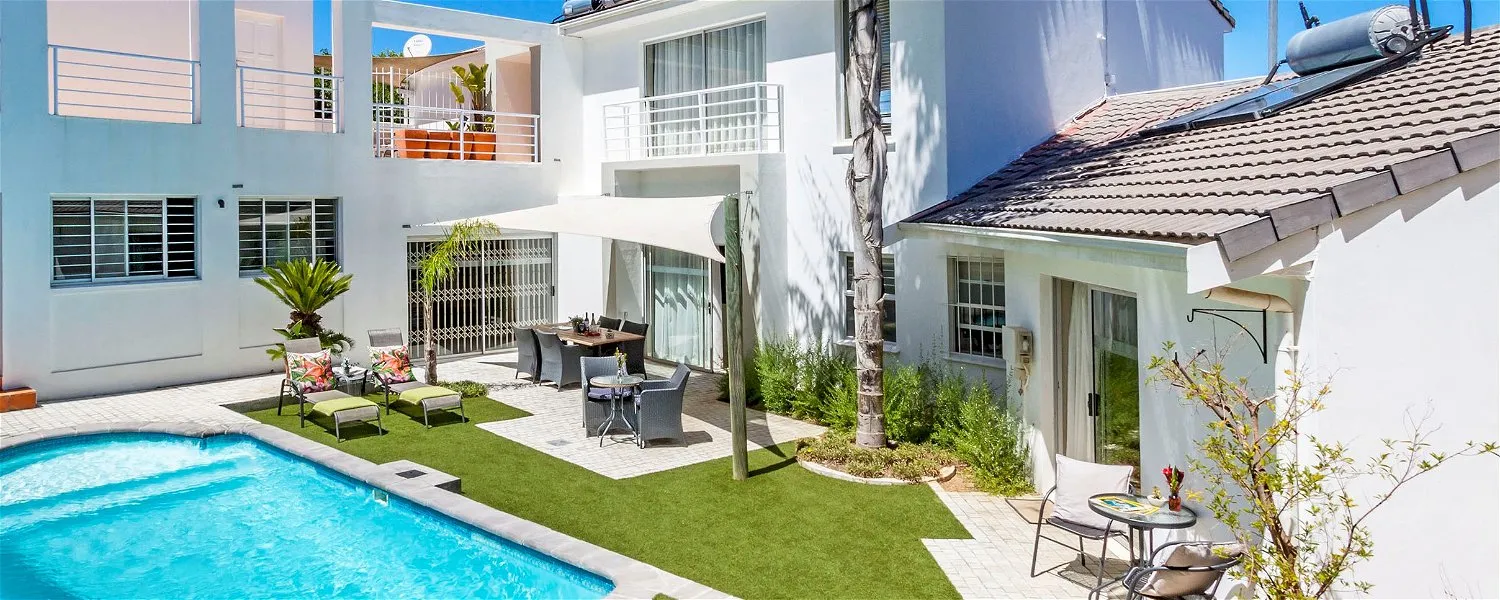 Modern house with pool patio furniture and artificial grass in a sunny setting