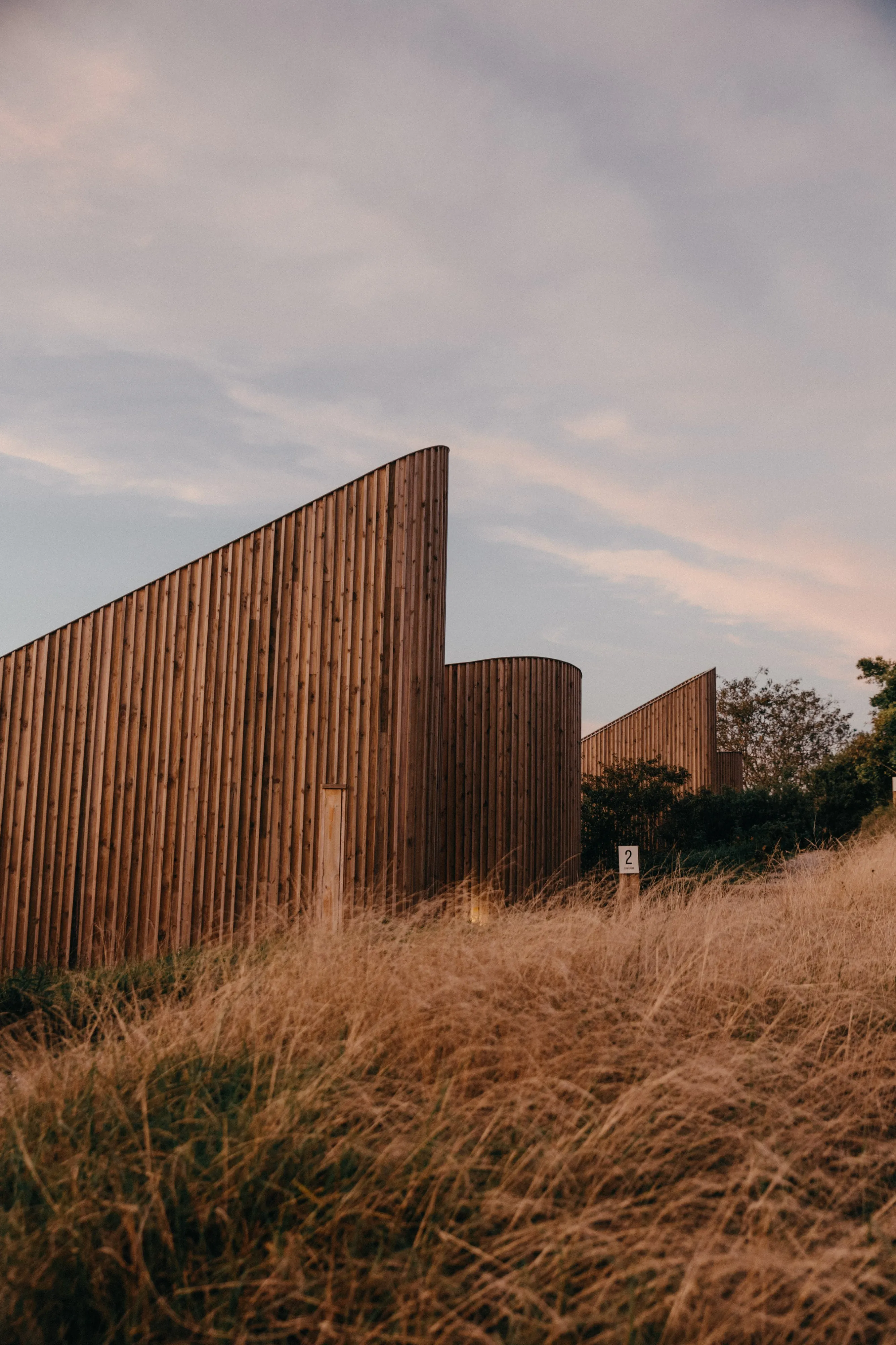 Modern wooden buildings on a grassy hill at sunset