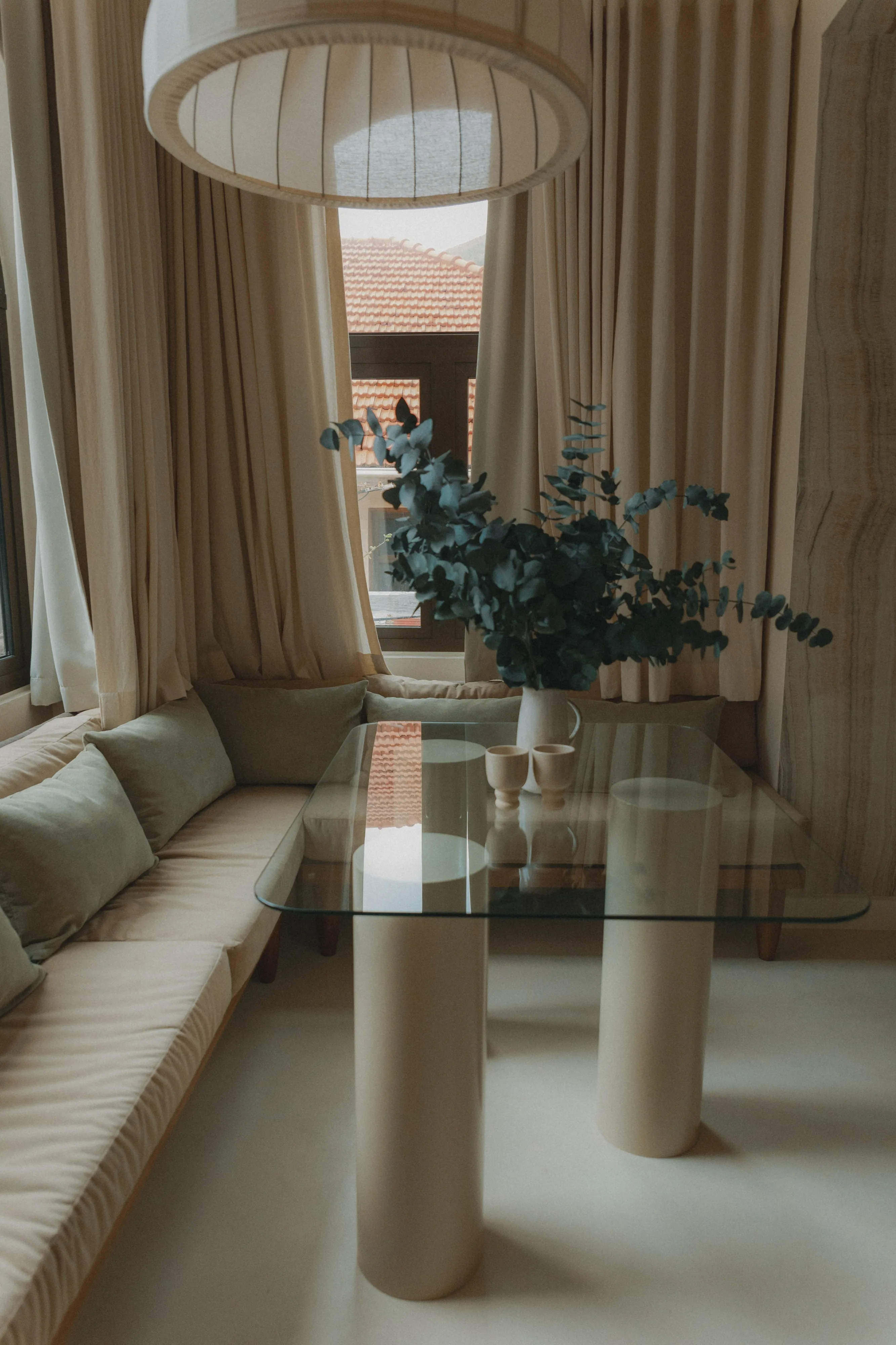 Beige living room with glass table green plant and large window