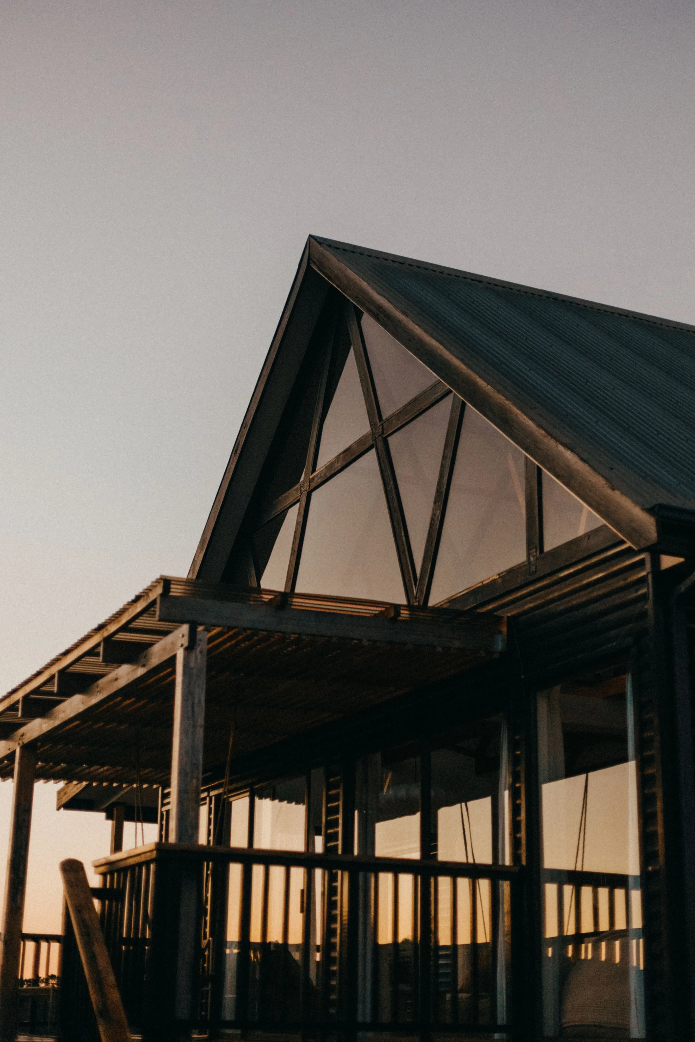 Modern house with large glass windows and a sloped roof at sunset