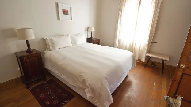 Neat bedroom with a white bed wooden floor and large window