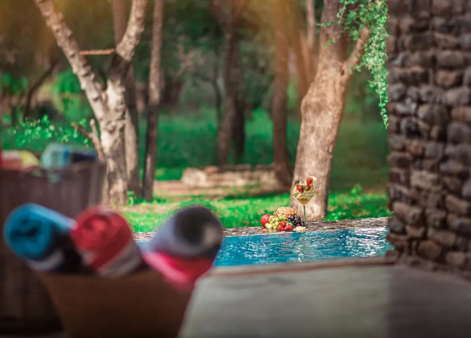 Rolled towels in a basket near a pool with fruit in the water