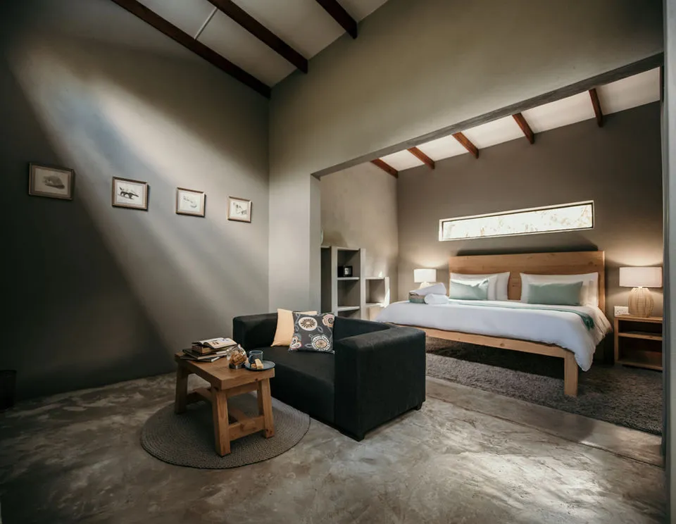 Modern bedroom with high ceiling large bed sofa and concrete floor