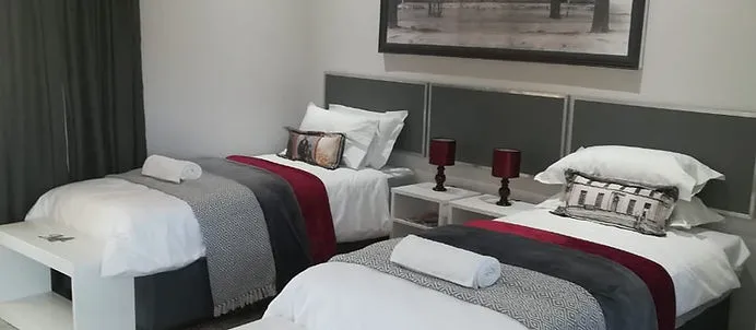 Two neatly made single beds in a modern bedroom with a framed picture