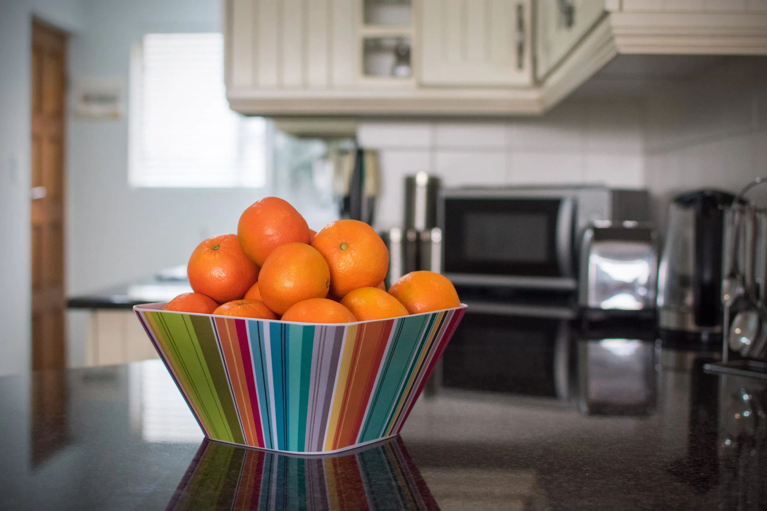 Bowl of oranges on a kitchen counter with appliances in the background