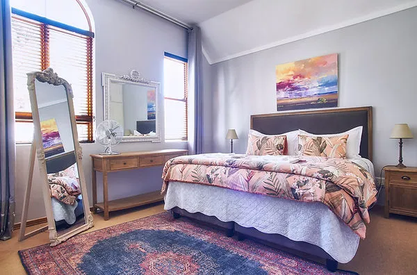 Bedroom with large bed floral bedding mirror and artwork on the wall