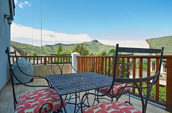 Balcony with table chairs and mountain view under a clear blue sky