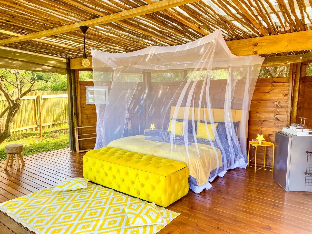Wooden cabin bedroom with yellow accents mosquito net and outdoor setting