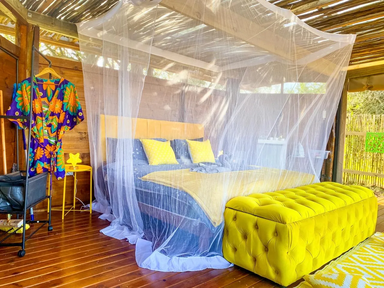 Bed with mosquito net in a wooden room with colorful decor