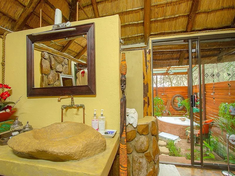 Rustic bathroom with stone sink mirror and outdoor shower area