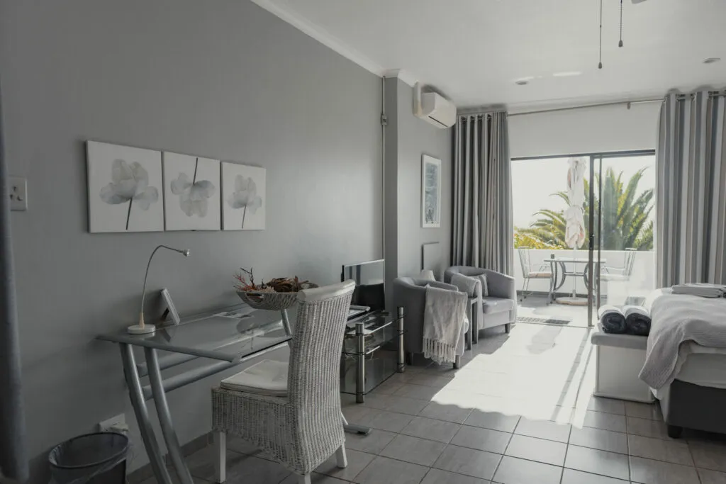 Modern bedroom with desk chair sofa and balcony view