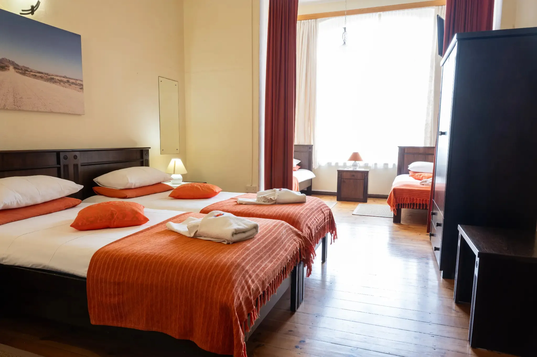 Hotel room with two large beds one small bed and wooden floor