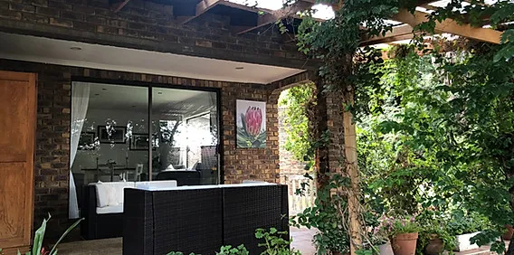 Outdoor patio with seating plants and a view into a living room