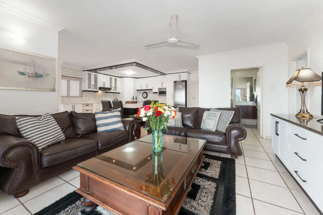 Living room with brown leather sofas coffee table and flowers on the table