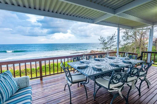 Outdoor dining area with ocean view wooden deck and set table