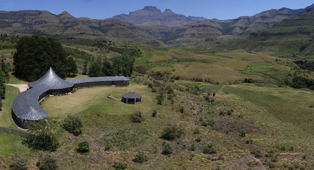 Modern building in a lush valley with mountains in the background
