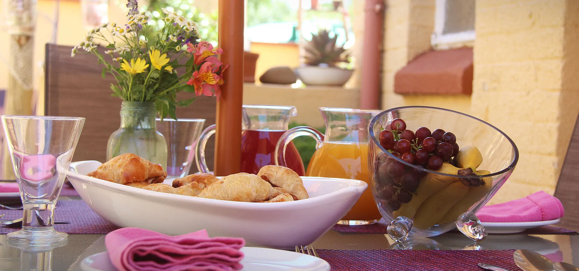 Outdoor breakfast table with pastries fruit juice and flowers