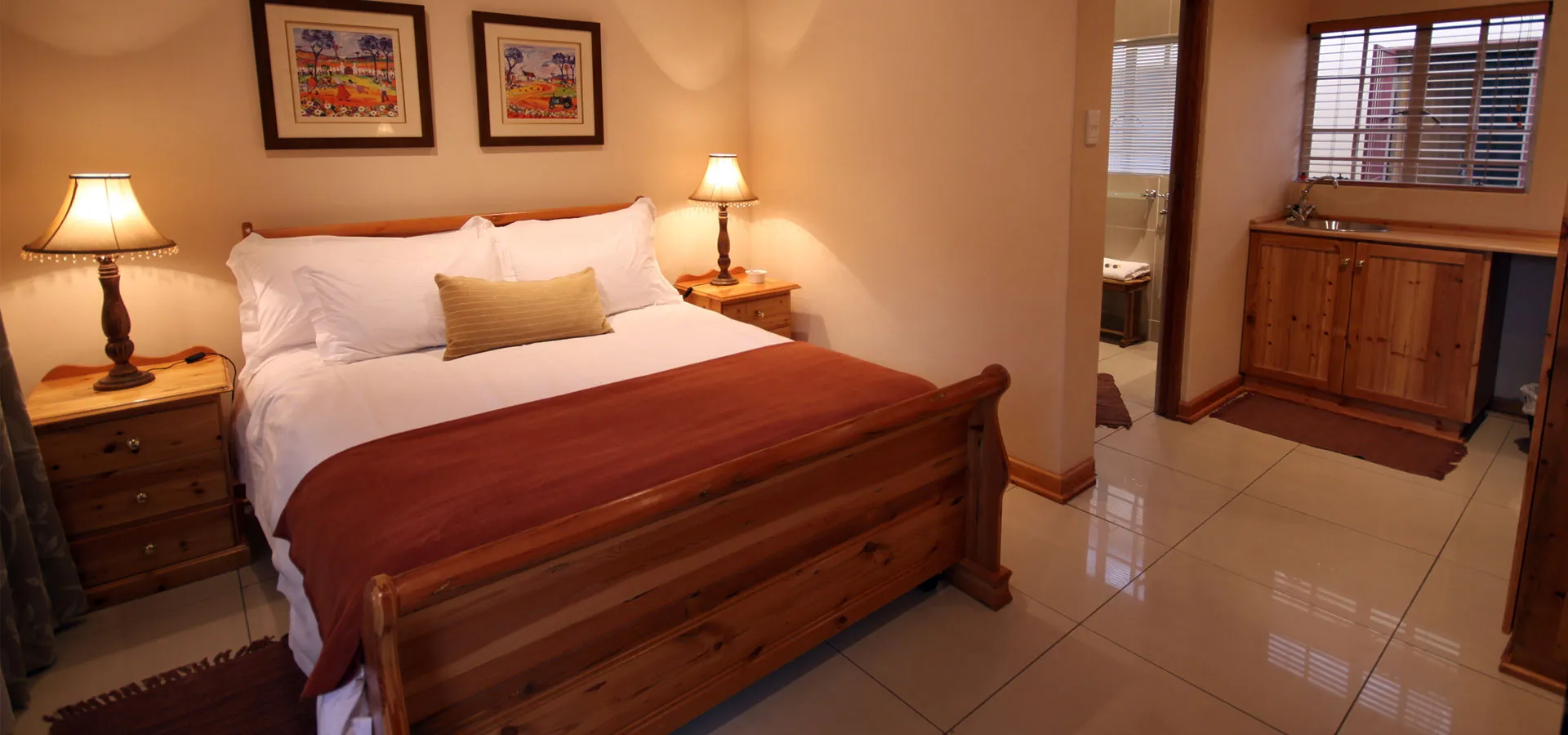 Cozy bedroom with wooden furniture white bedding and an attached bathroom