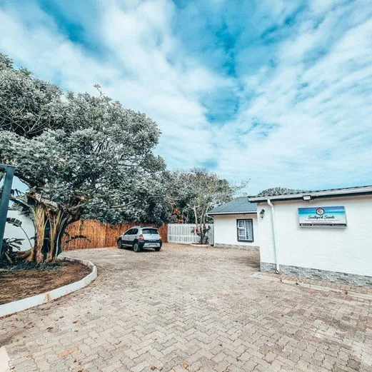 White building with sign parked car and paved driveway under blue sky