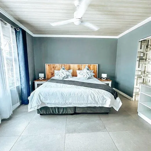 Modern bedroom with large bed ceiling fan and tiled floor