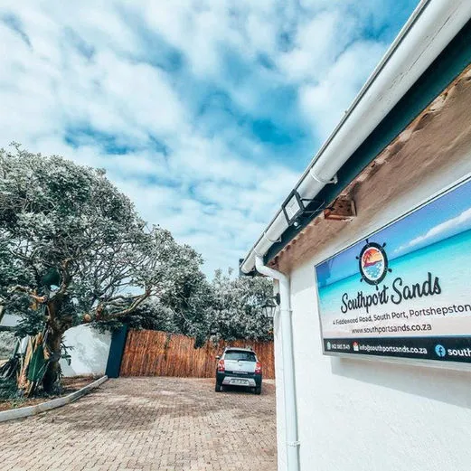 Sign for Southport Sands with a driveway and trees under a blue sky