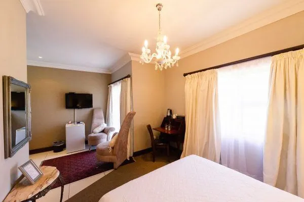 Hotel room with bed desk chairs TV and chandelier