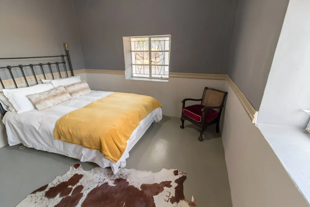 Bedroom with bed yellow blanket cowhide rug and wooden chair