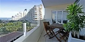 Balcony with wooden table and chairs potted plant and view of buildings and greenery