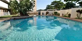 Swimming pool with surrounding greenery and buildings in the background