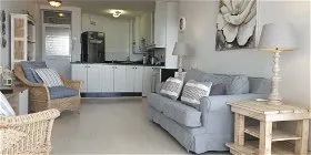 Light living room with sofa wicker chairs and open kitchen view
