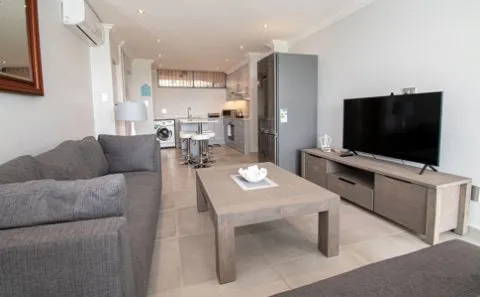 Modern living room with sofa TV coffee table and open kitchen view