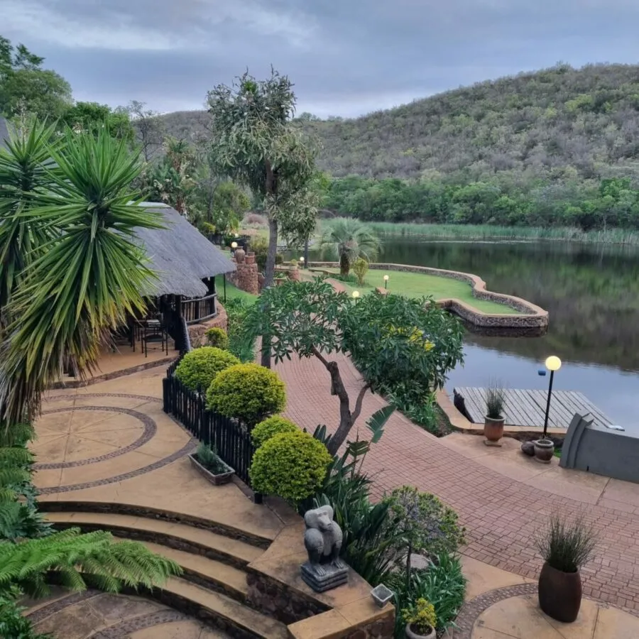 Scenic lakeside view with lush greenery stone pathway and distant hills