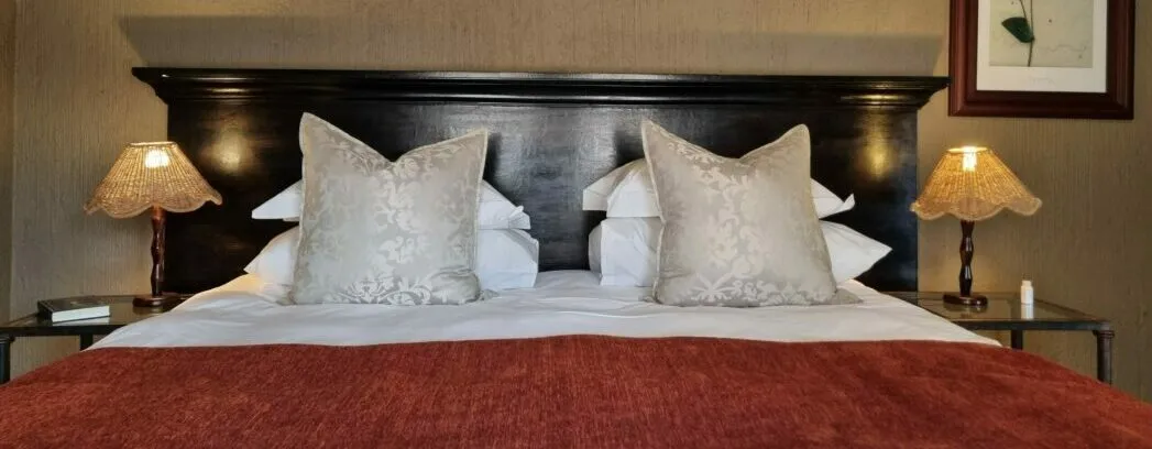 Neatly made bed with white pillows and red blanket in a bedroom setting