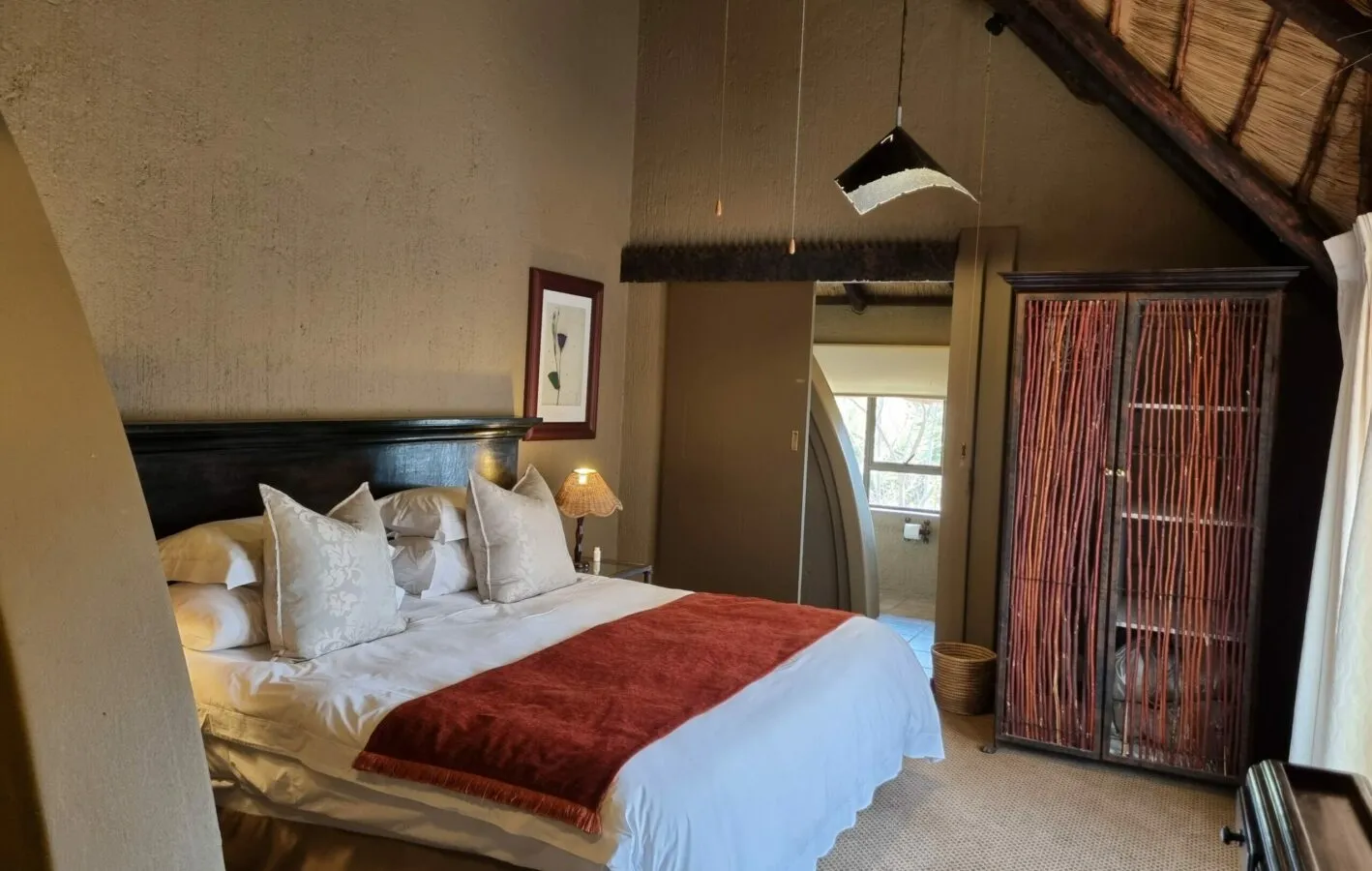 Cozy bedroom with large bed red throw and wooden wardrobe under slanted ceiling