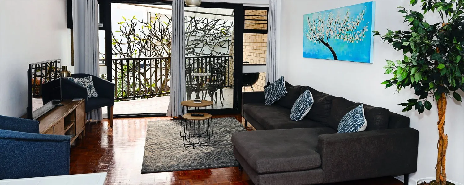 Modern living room with large window dark sofa and colorful wall art