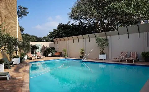 Swimming pool with lounge chairs trees and a building in the background