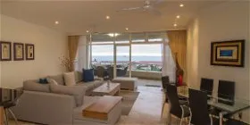 Modern living room with sofa dining area and large windows with ocean view