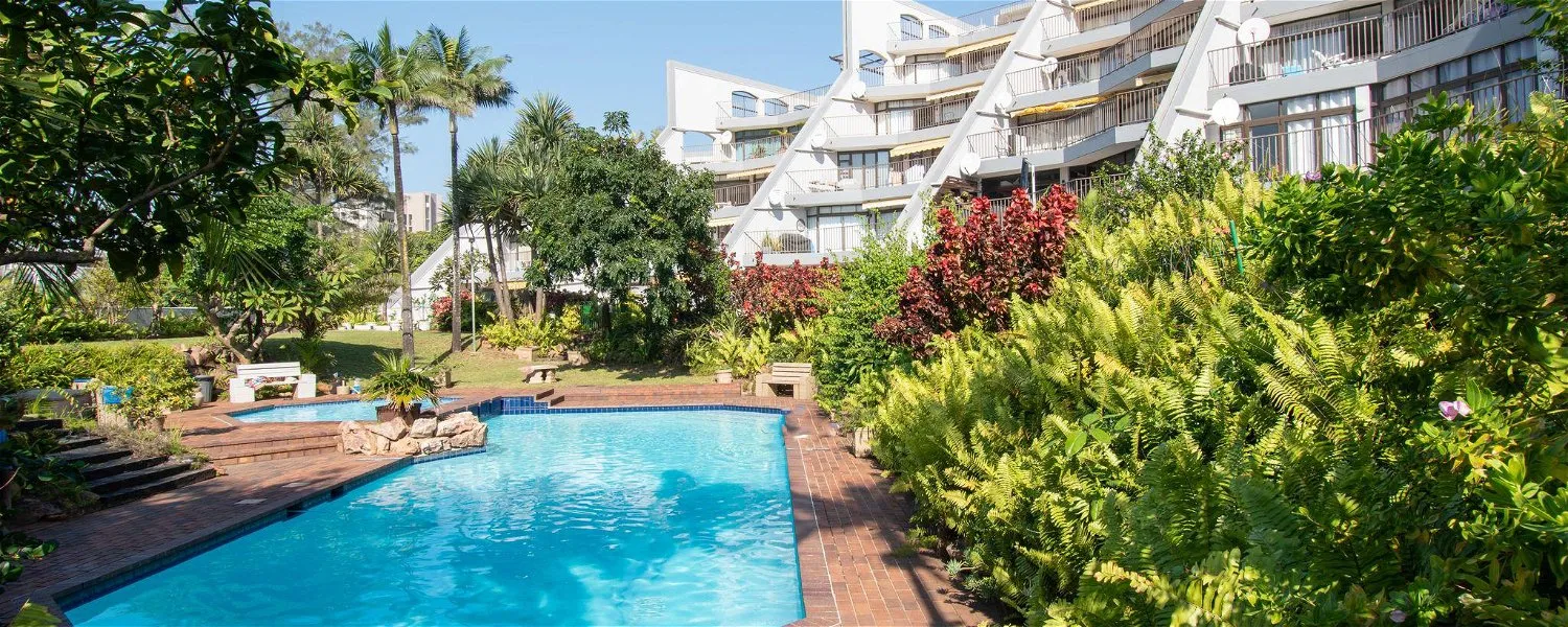 Swimming pool surrounded by lush greenery and modern white buildings
