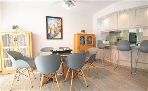 Modern dining area with table chairs and kitchen bar stools in a bright room