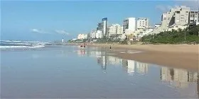 Beach with calm water sandy shore and city buildings in the background