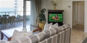 Living room with a view of the ocean TV on and balcony furniture