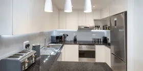 Modern kitchen with black countertops stainless steel appliances and pendant lights