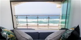 View of ocean from a cozy sofa with pillows through a large window