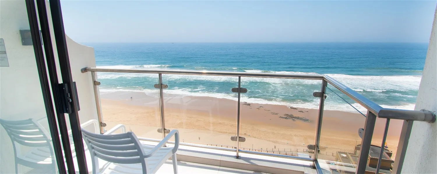Balcony view of ocean and sandy beach with two chairs