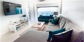 Modern living room with large window sofas TV and ocean view