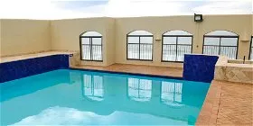 Swimming pool on a rooftop with ocean view through arched windows