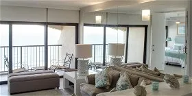 Ocean view living room with large windows sofa and bedroom in the background